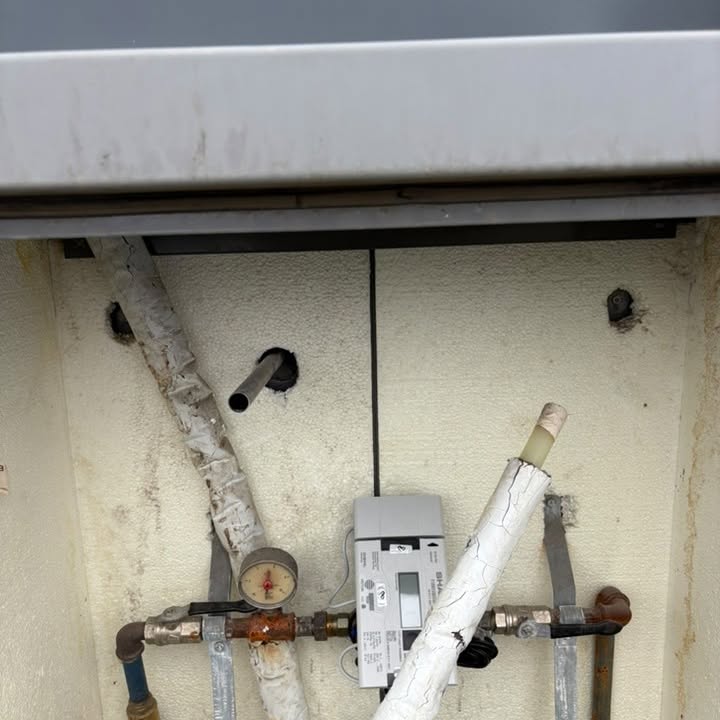 Tengigrind með mæli og einangruðum lögnum undir lofti.